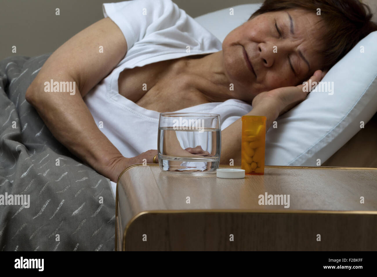 Close up of an open bottle of medicine and a glass of water on