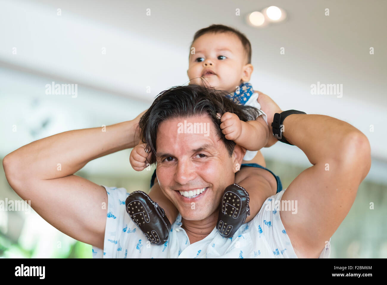 Multi ethnic family - Father carrying baby son on shoulders Stock Photo