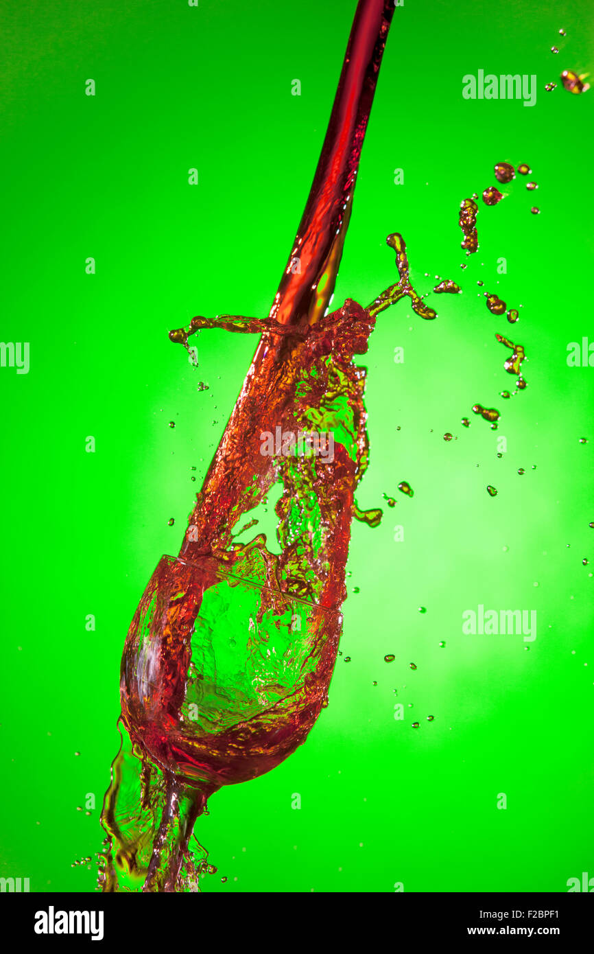 Red wine poured heavy into a wine glass making a splash. Stock Photo