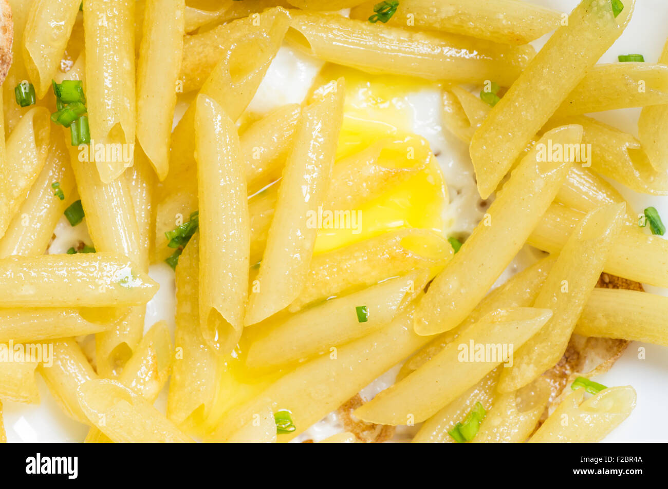 Italian penne pasta on a plate with egg closeup top view Stock Photo
