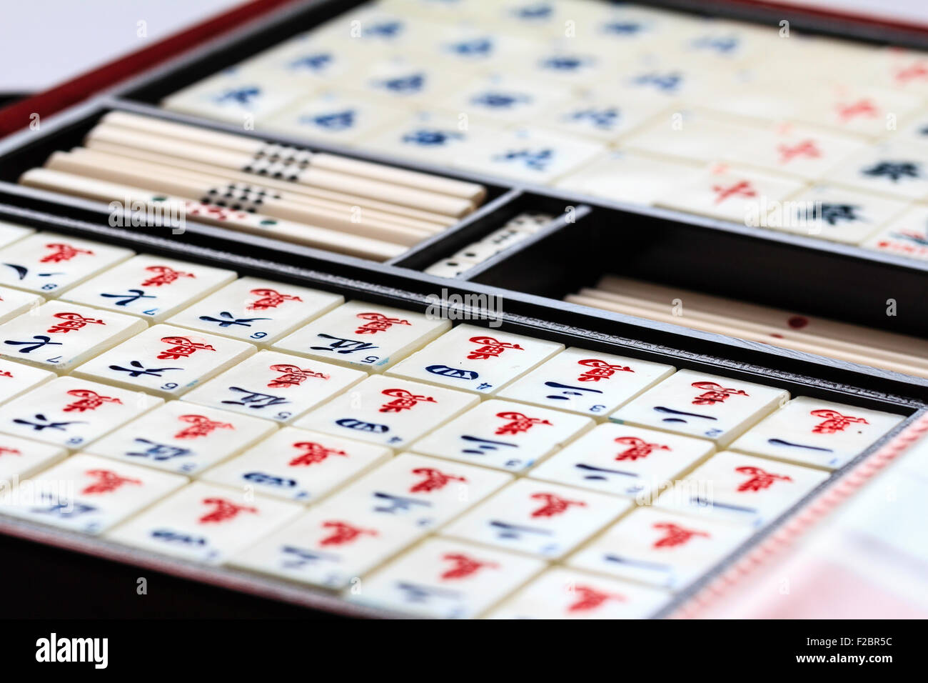 Mahjong, Mah jongg gambling open box, with contents displayed, various tile or card suits, sets arranged by number on plain white background Stock Photo