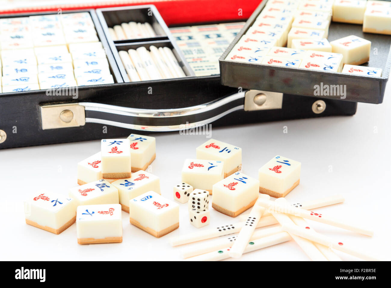 Mahjong, Mah jong gambling box set, open with contents partly remove. Various black trays with sets or suits of cards and tiles plain white background. Stock Photo