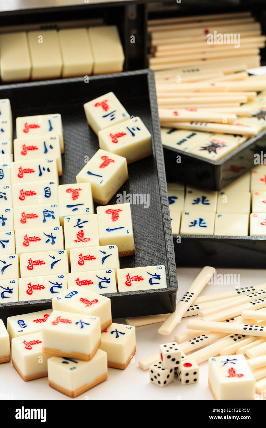 Mahjong, Mah jong gambling box set, open with contents partly remove. Various black trays with sets or suits of cards and tiles plain white background. Stock Photo