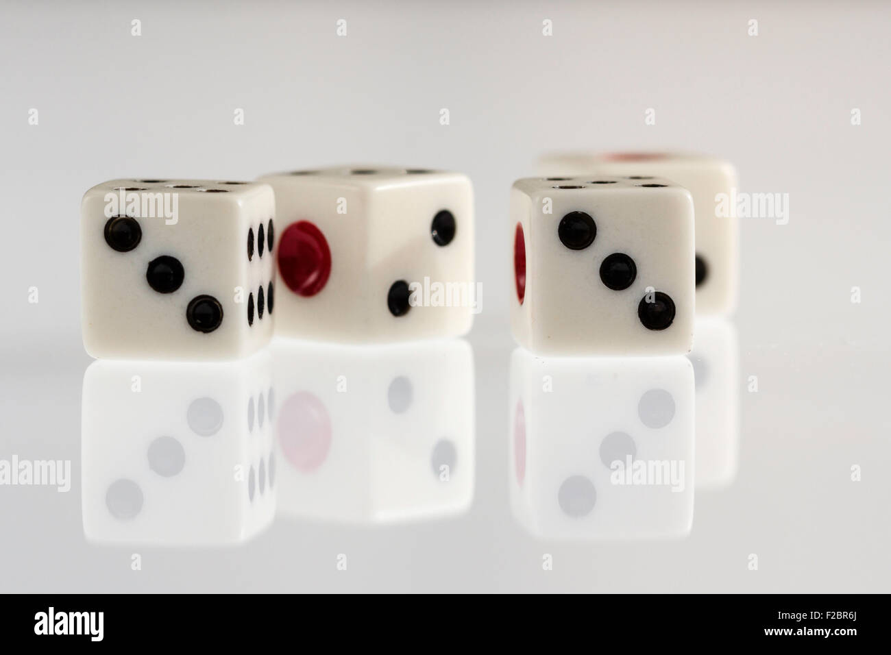 Four white dice with black spots and red single one on illuminated