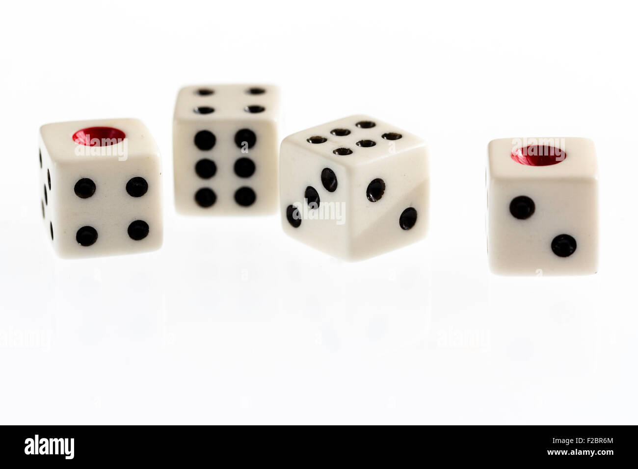 Four white dice with black spots and red single one on illuminated