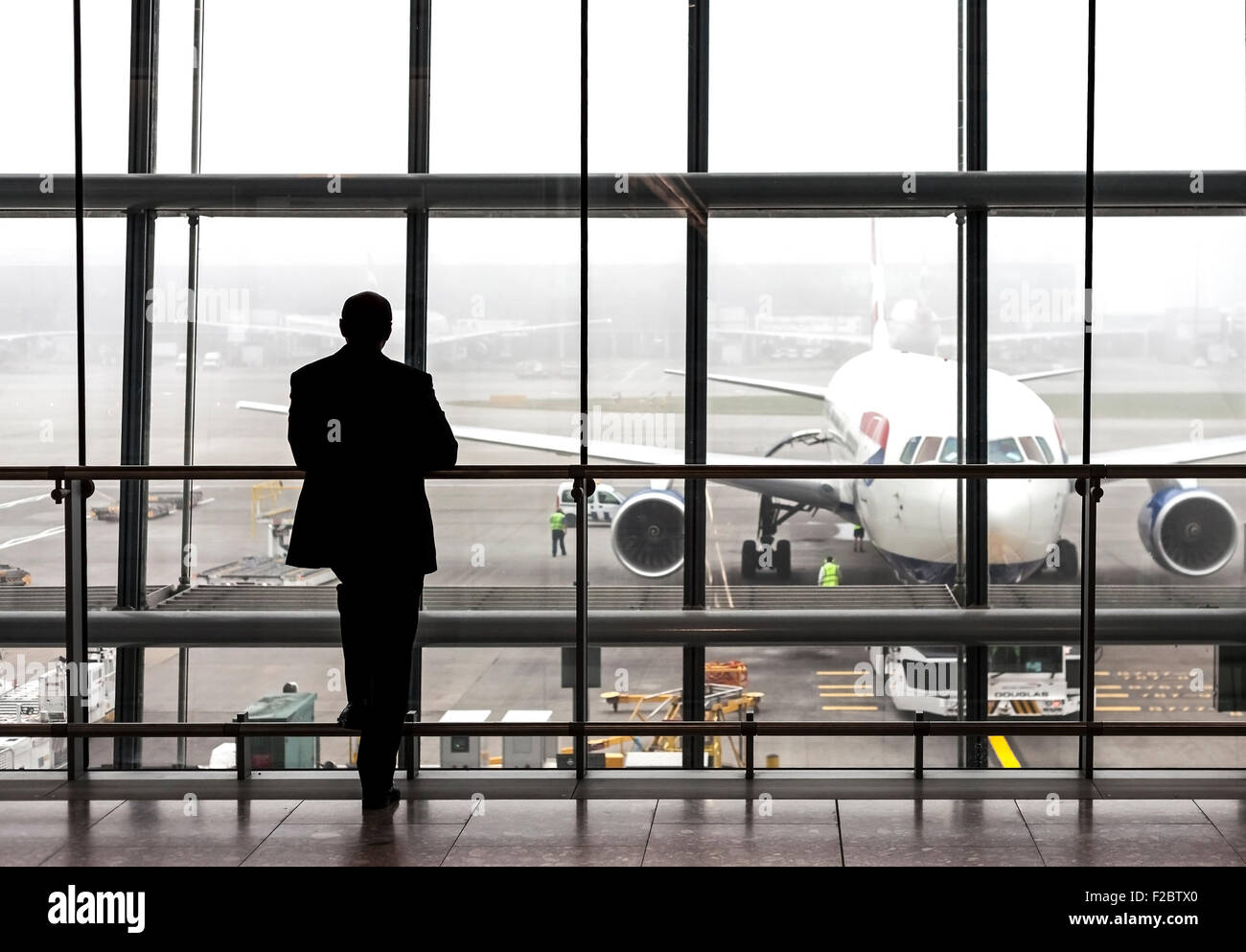 London, UK - August 14, 2015: Silhouette of a traveler waiting for a plane at the Heathrow airport departure hall on a rainy day Stock Photo