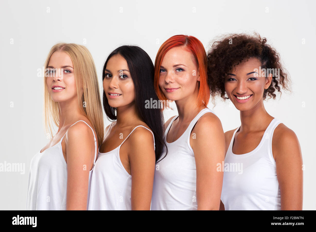 Portrait of a four smiling multi ethnic women standing isolated on a white background and looking at camera Stock Photo