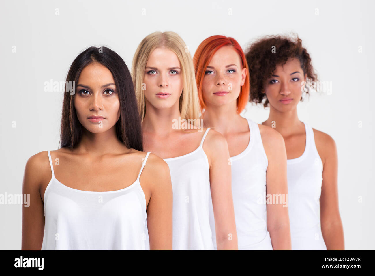 Portrait of a four serious women with colourful hair standing in a row isolated on a white background Stock Photo