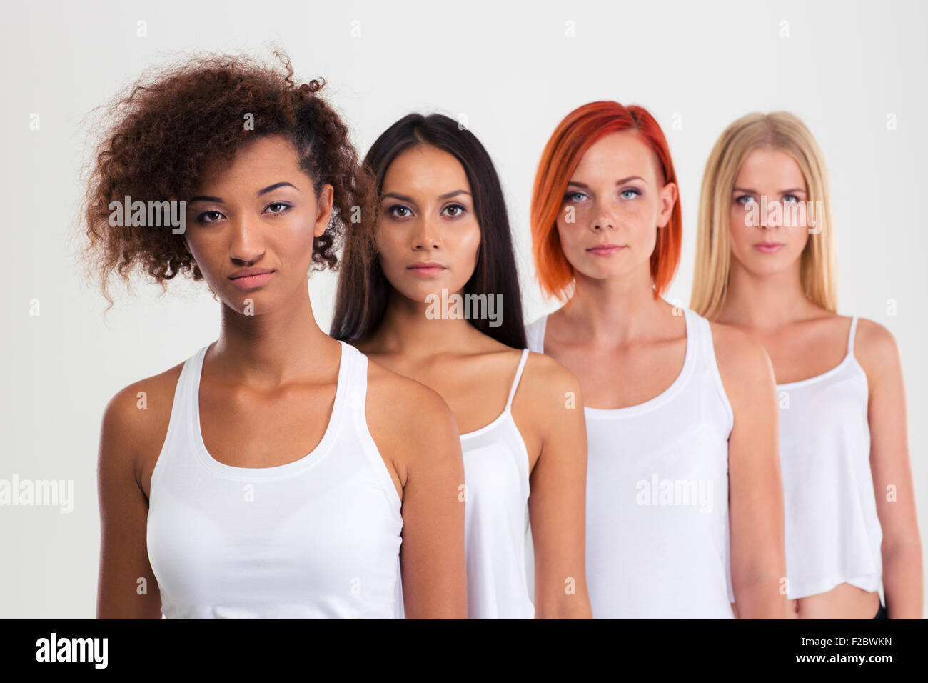 Portrait of a beautiful four women standing in a row isolated on a white background and looking at camera Stock Photo