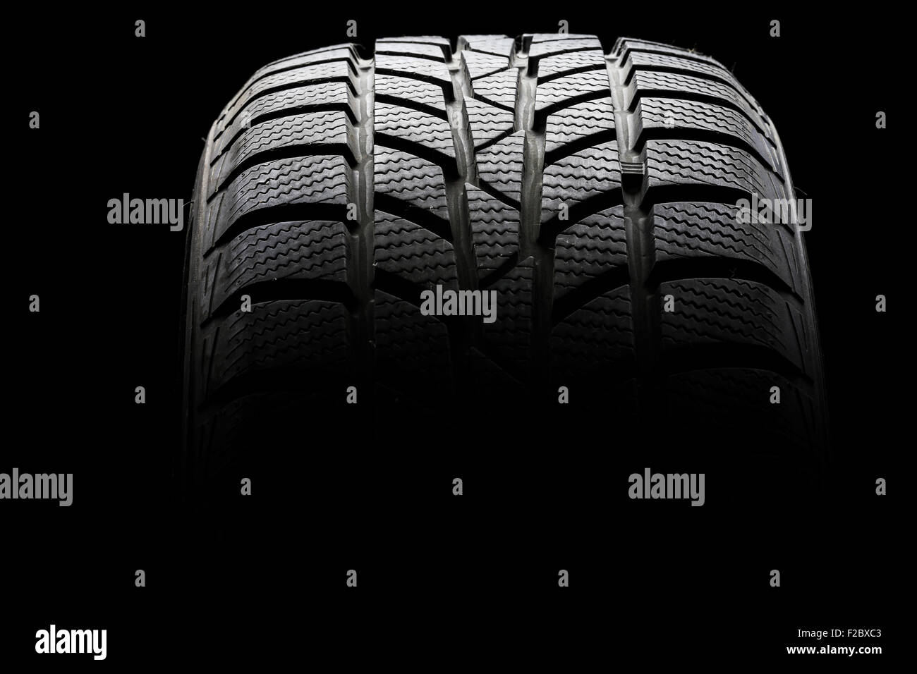 Studio shot of a black car tire in a dark ambient on black background Stock Photo