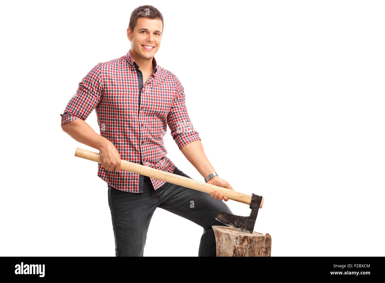 Young guy in a checkered shirt holding an ax and posing behind a log isolated on white background Stock Photo