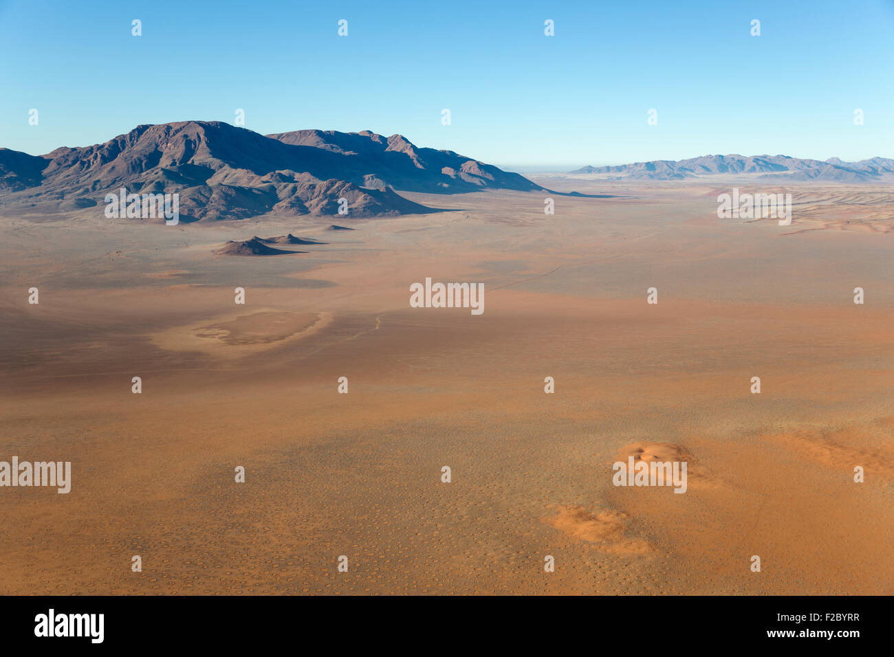 Arid desert plains with so-called Fairy Circles and isolated mountain ridges at the edge of the Namib Desert, aerial view from a Stock Photo