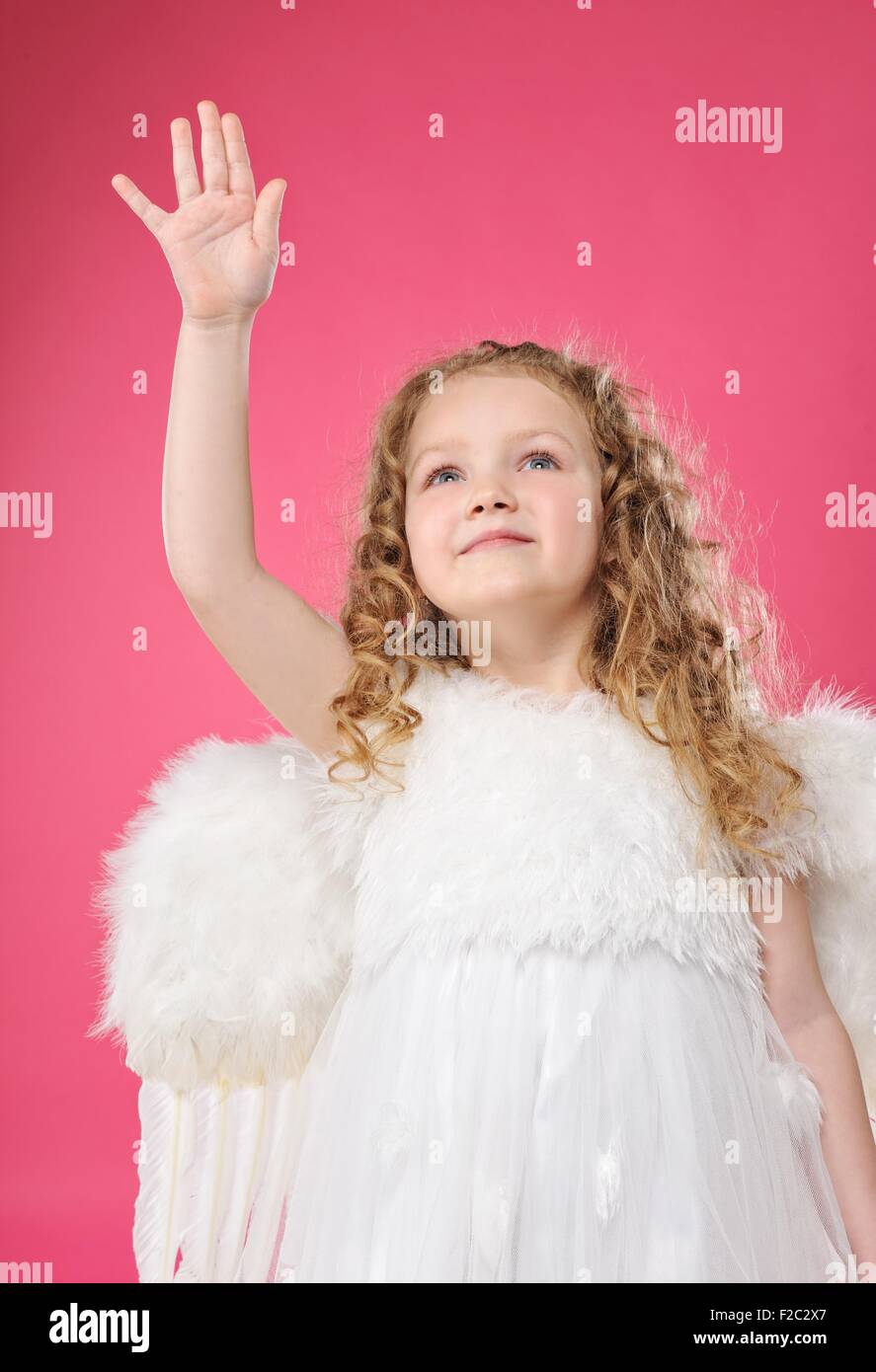 Beautiful little angel girl isolated on pink background Stock Photo