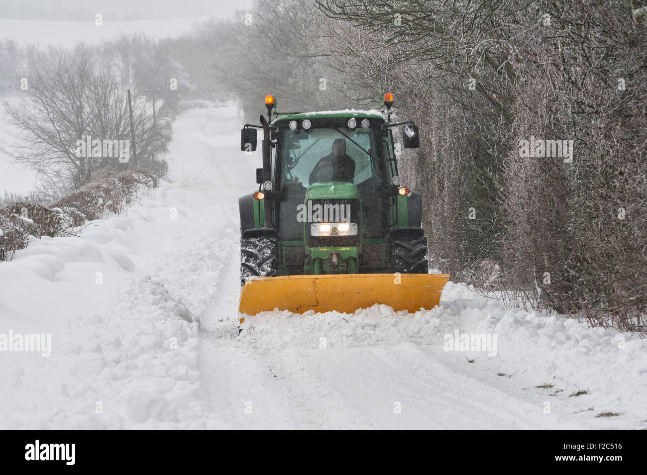 Wales, UK. A tractor fitted with a snowplough clearing a lane on