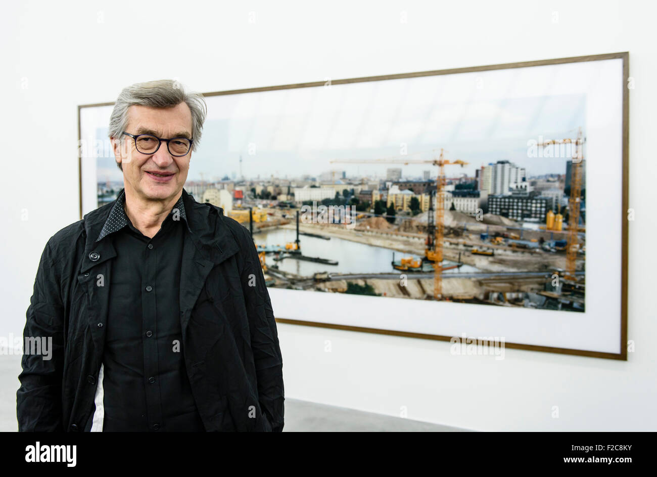 Berlin, Germany. 16th Sep, 2015. Movie director and photographer Wim Wenders poses in front of his photograph entitled 'Potsdamer Platz' from 1995 during a press conference for the exhibition 'Time Capsules. By The Side Of The Road. Wim Wenders' at the Berlin Art Week in Berlin, Germany, 16 September 2015. Photo: CLEMENS BILAN/dpa/Alamy Live News Stock Photo