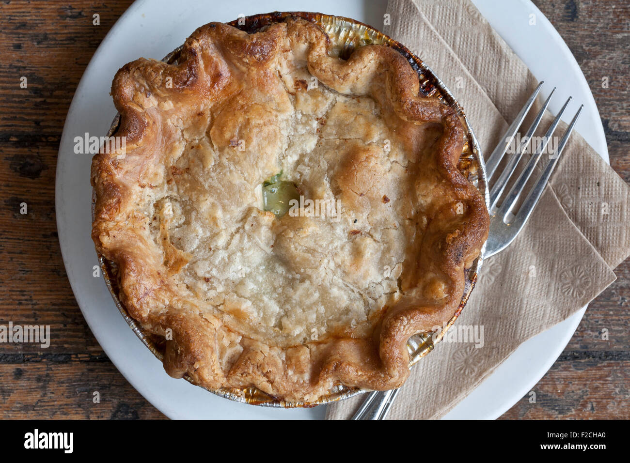 overhead view of chicken pot pie on white plate with napkin and fork Stock Photo