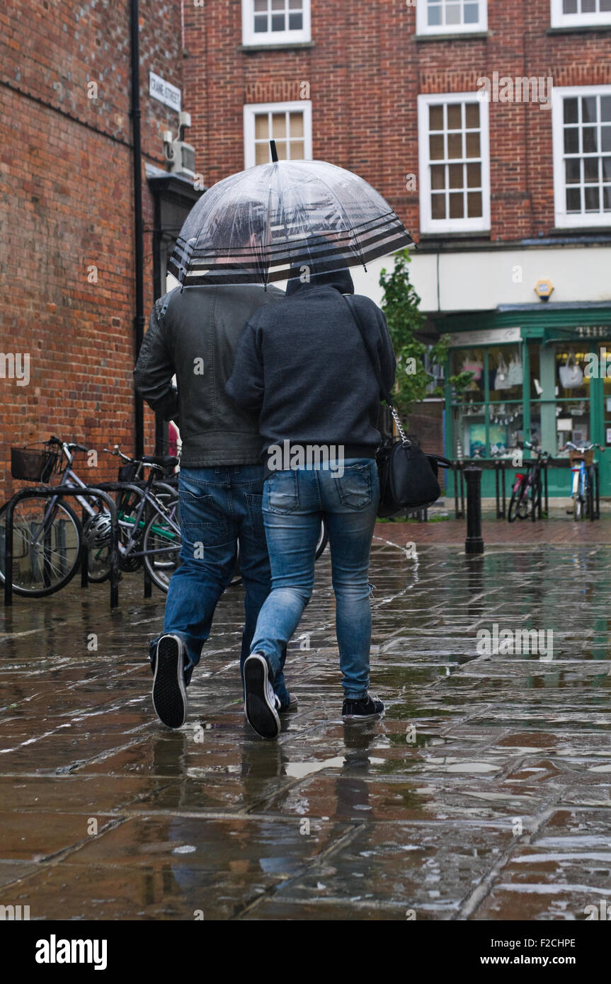 Chichester, West Sussex, England. Two people share an umbrella walking through the town on a rainy day. Stock Photo