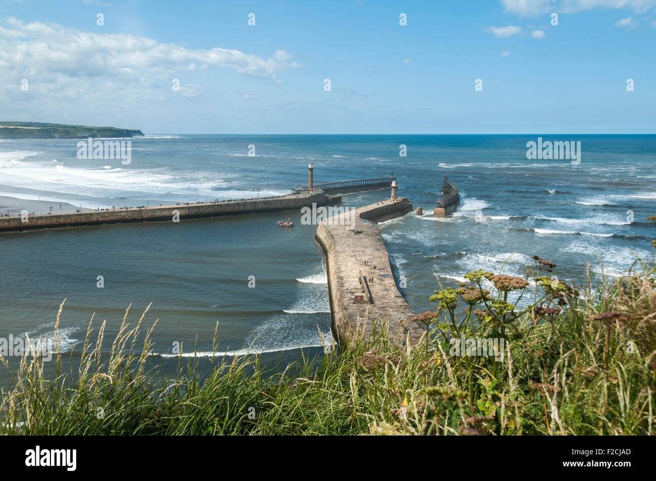 The piers of Whitby Harbour with Sandsend Bay beyond. From the Haggerlythe cliff, Whitby, Yorkshire, England, UK Stock Photo