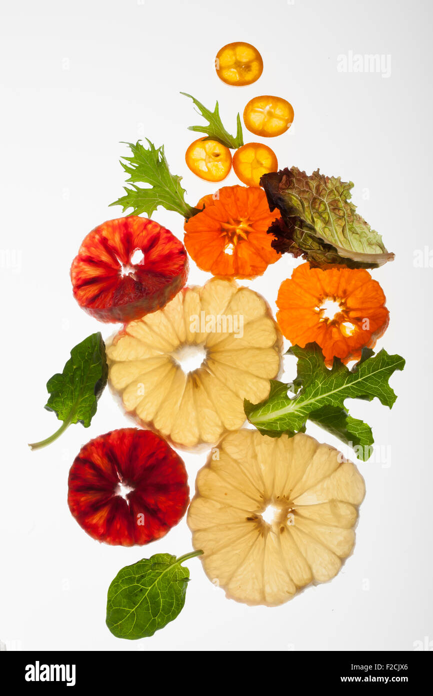 Cross section of peeled citrus fruit and greens back lit on white Stock Photo