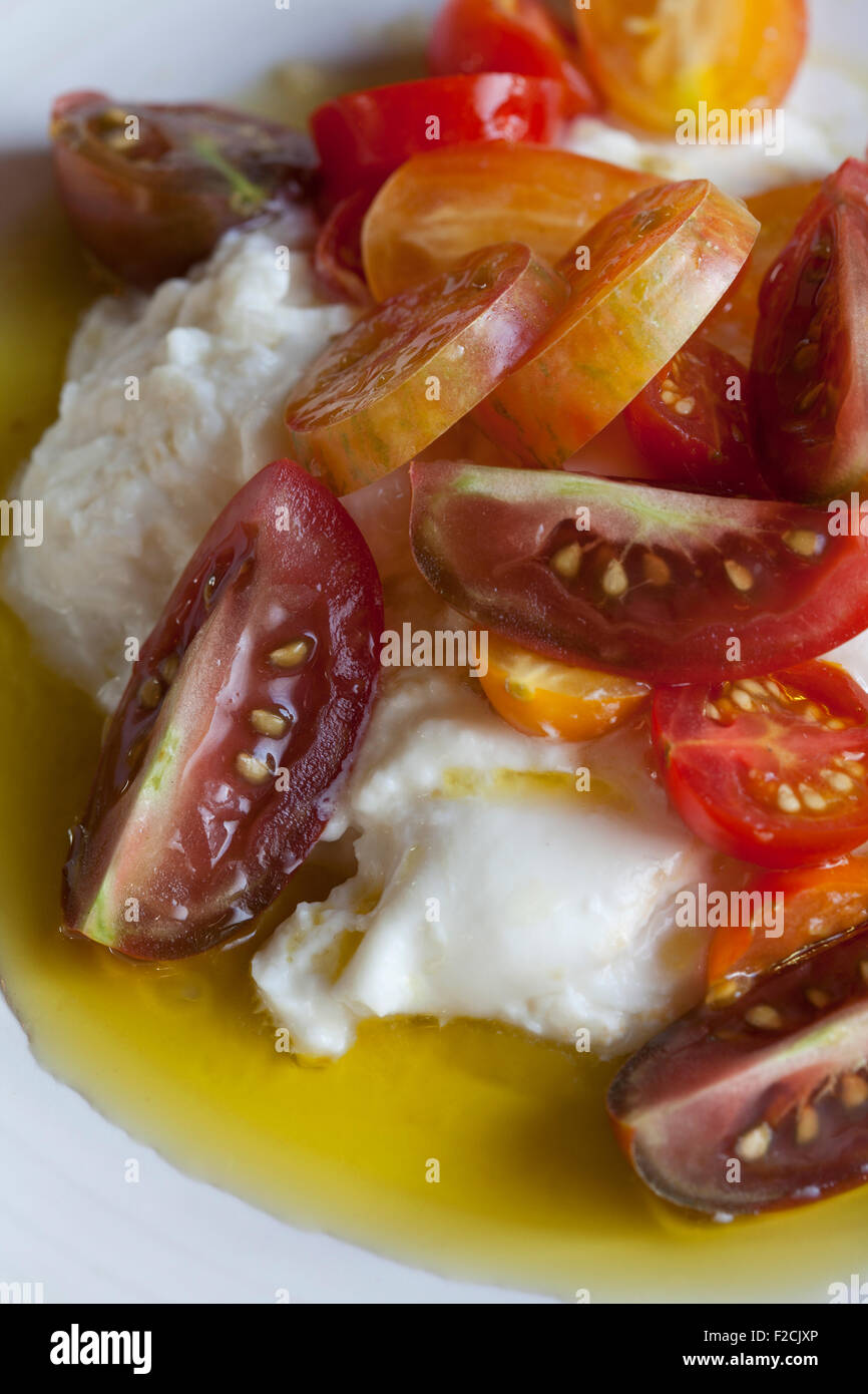 Looking down at burrata with cherry tomatoes, corona olive oil and sea salt salad Stock Photo