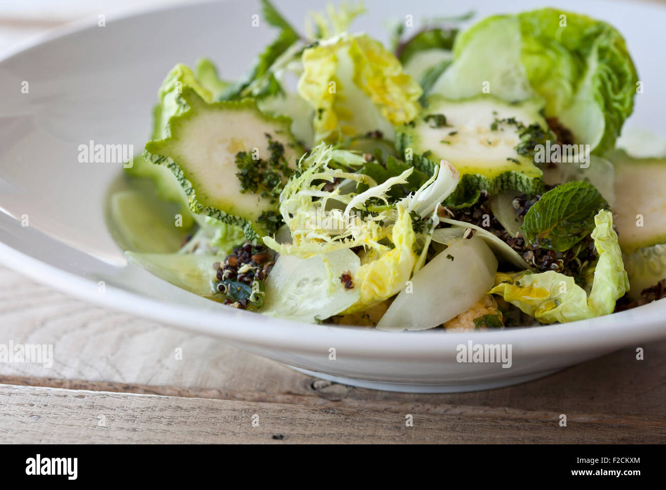 Side view of green salad with butter lettuce, radicchio, squash, in white bowl on table Stock Photo