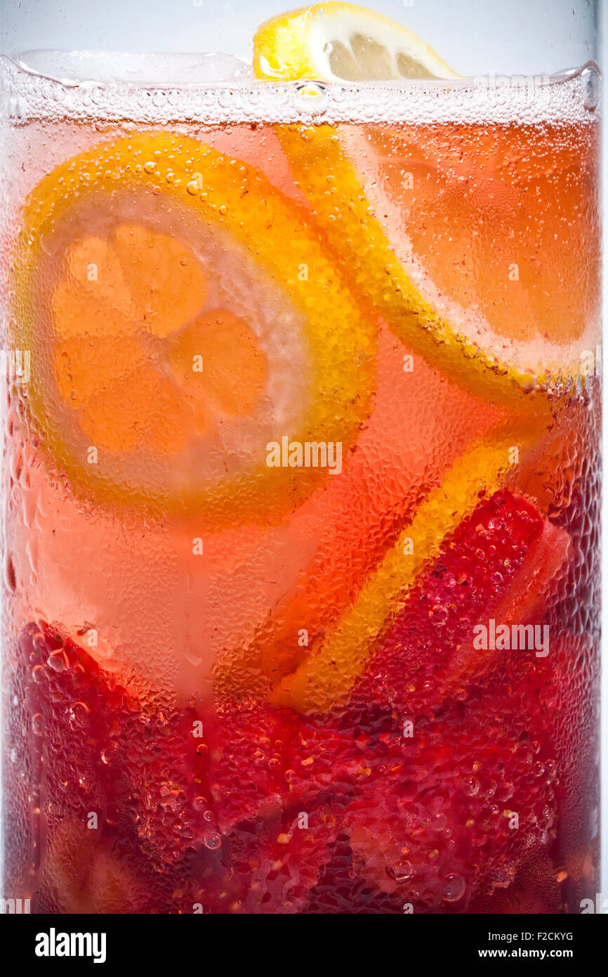 Side view of cropped cold drink with strawberries, lemon, bubbles, condensation Stock Photo