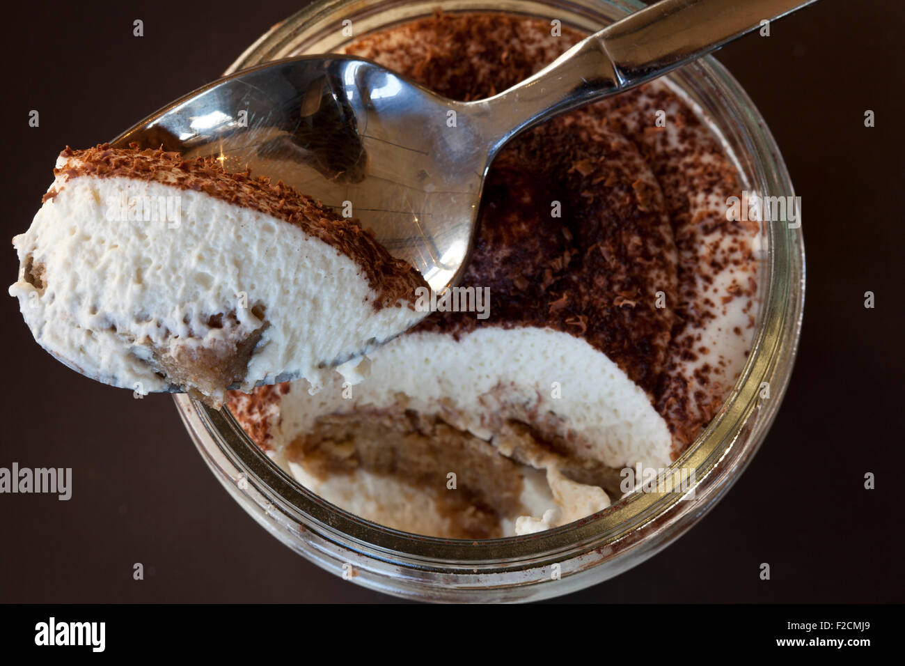 looking down at a jar of tiramisu with spoonful on dark background Stock Photo