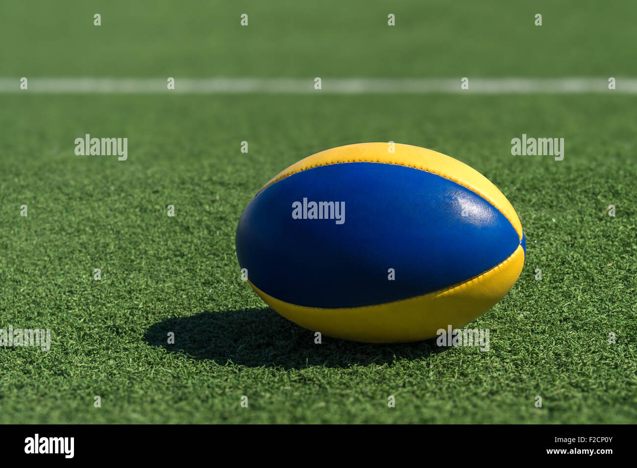 A rugby ball on a synthetic grass in front of the white line. Stock Photo