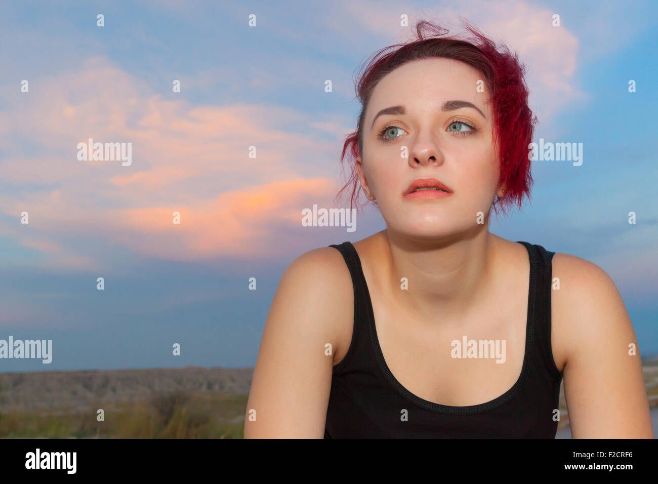 An attractive young woman posing with thoughtful, serious and silly expressions outdoors against a blue sky. Stock Photo