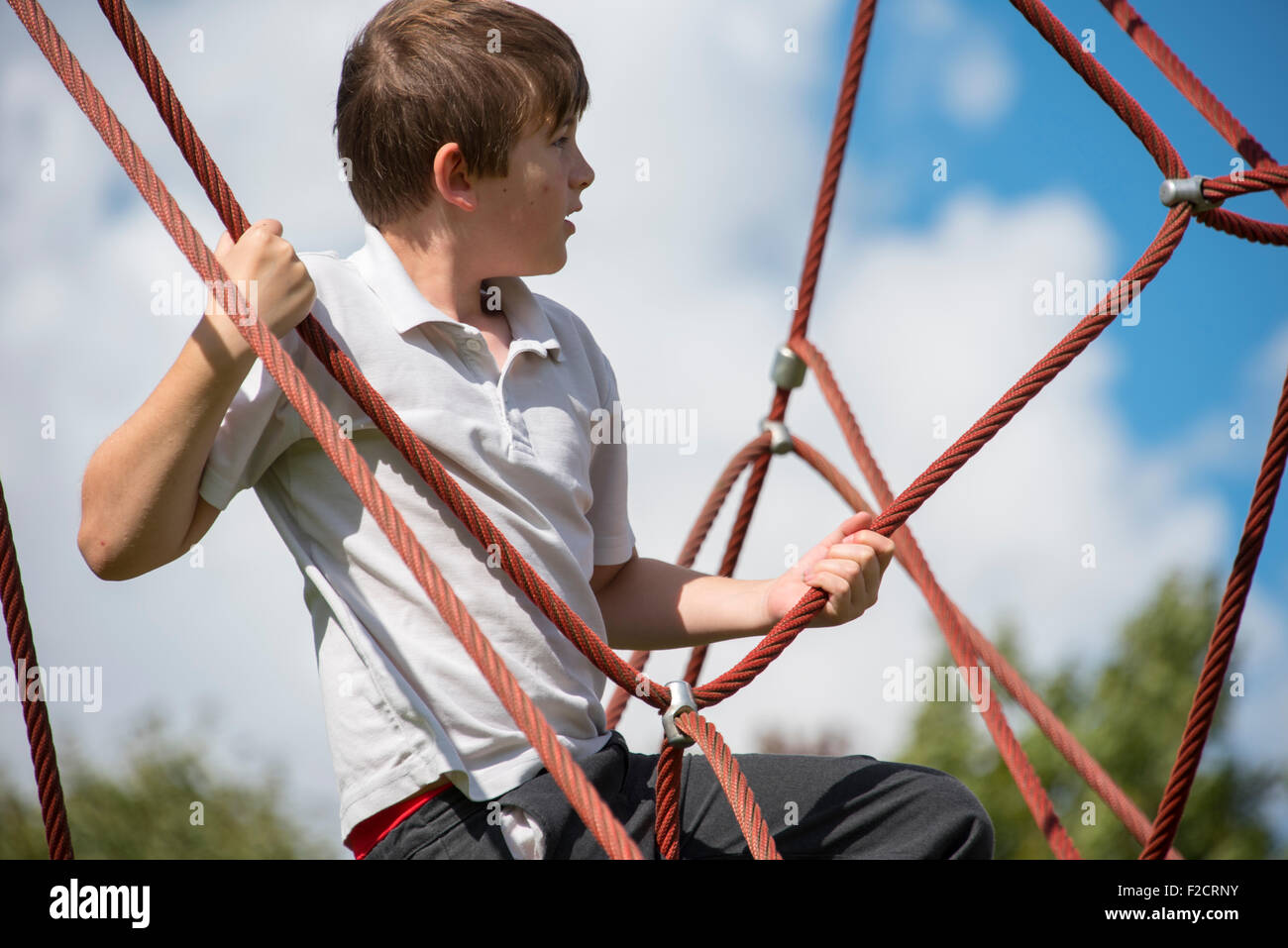 Boy climbing rope frame pyramid Stock Photo