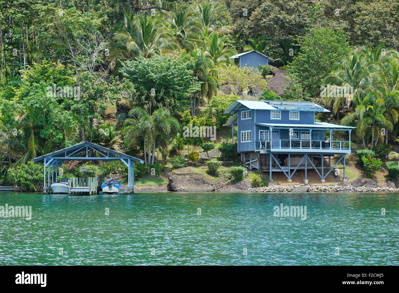 Coastal property on lush tropical shore with boats at dock and an house, Caribbean sea, Panama, Central America Stock Photo