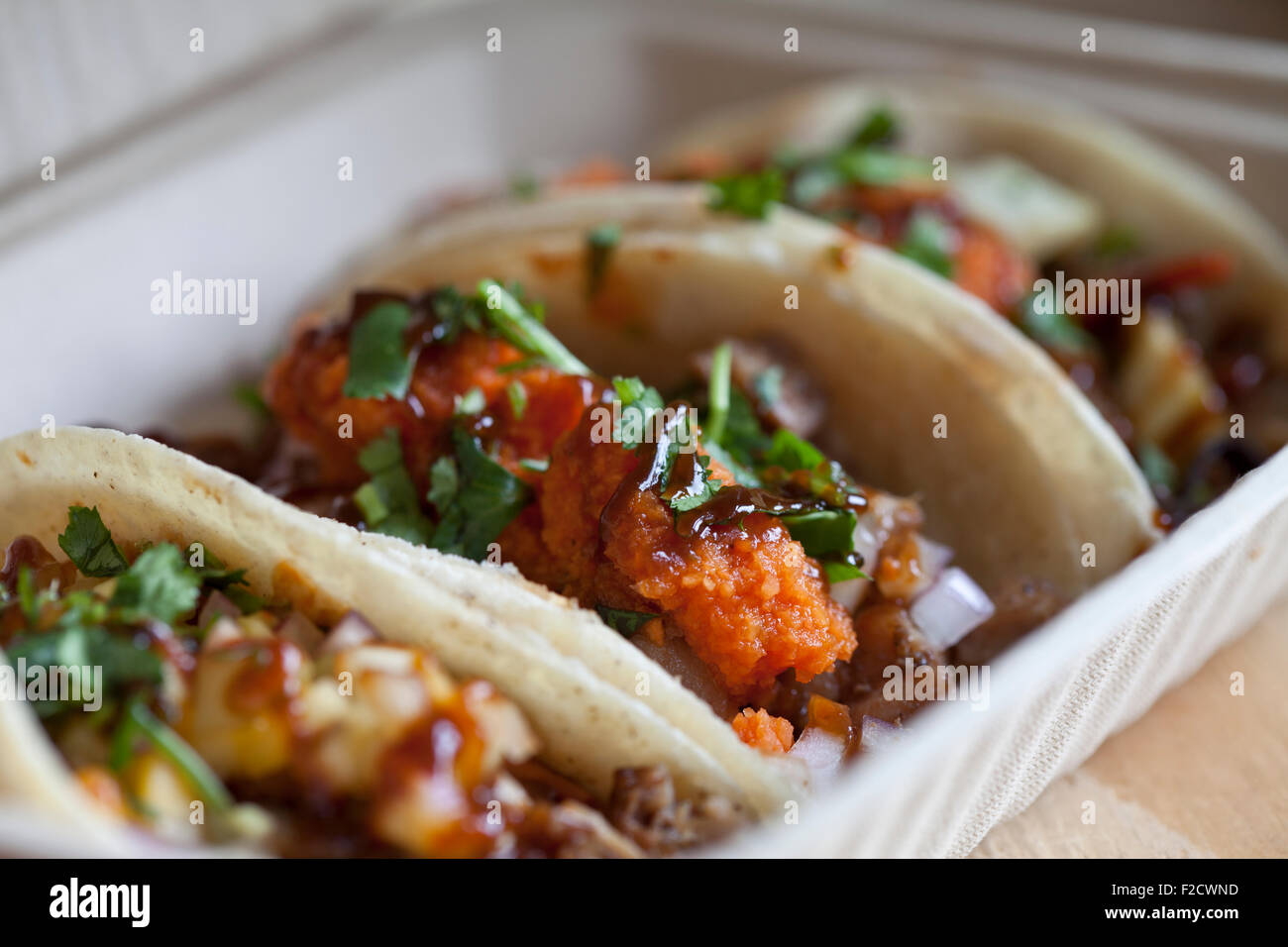 Diagonal side view  of three different tacos in an open to-go container Stock Photo