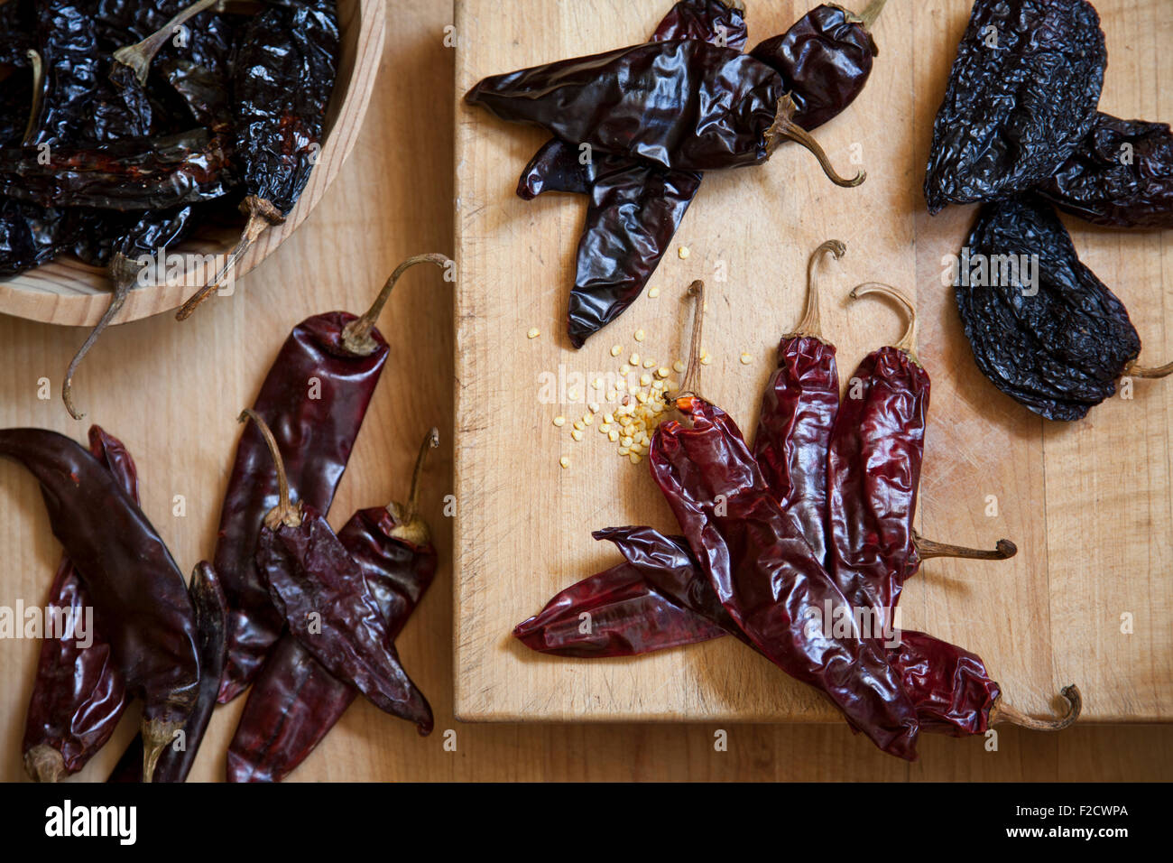 Overhead view of various dried peppers on several light wood surfaces Stock Photo