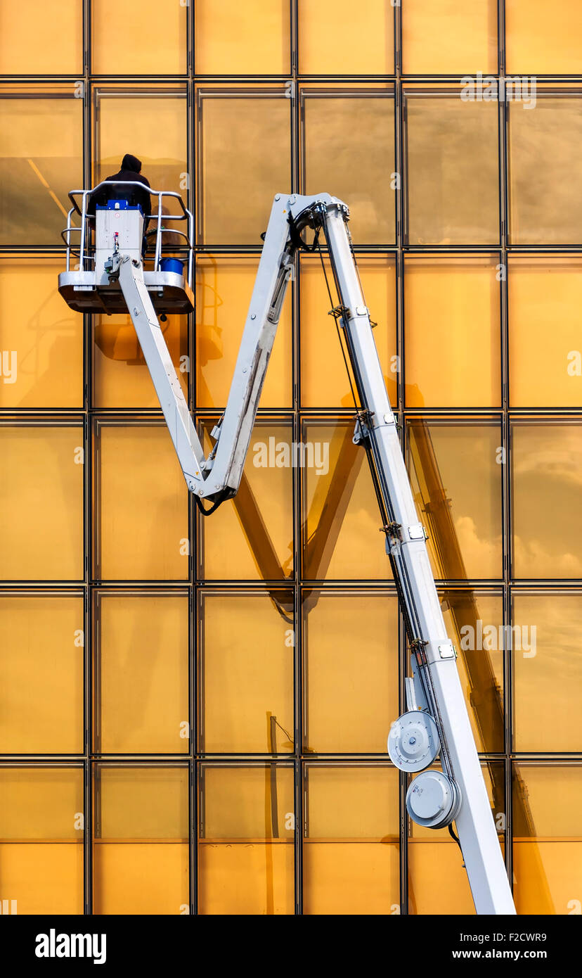 A window cleaner cleans the golden colored glass of a modern building