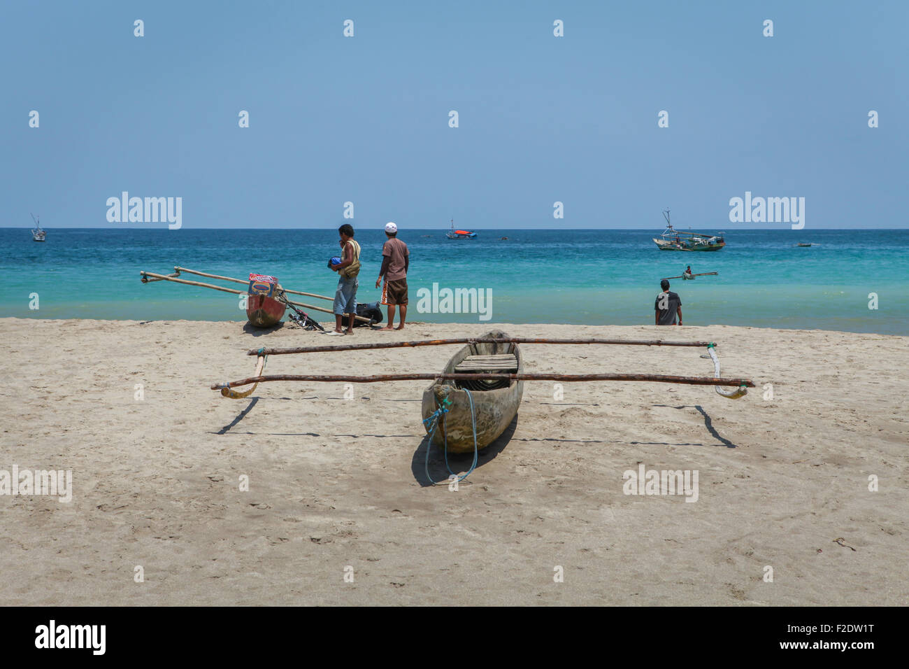 Canoes and fishermen on the beach in a background of Indian Ocean are seen in Wanokaka, West Sumba, East Nusa Tenggara, Indonesia. Stock Photo