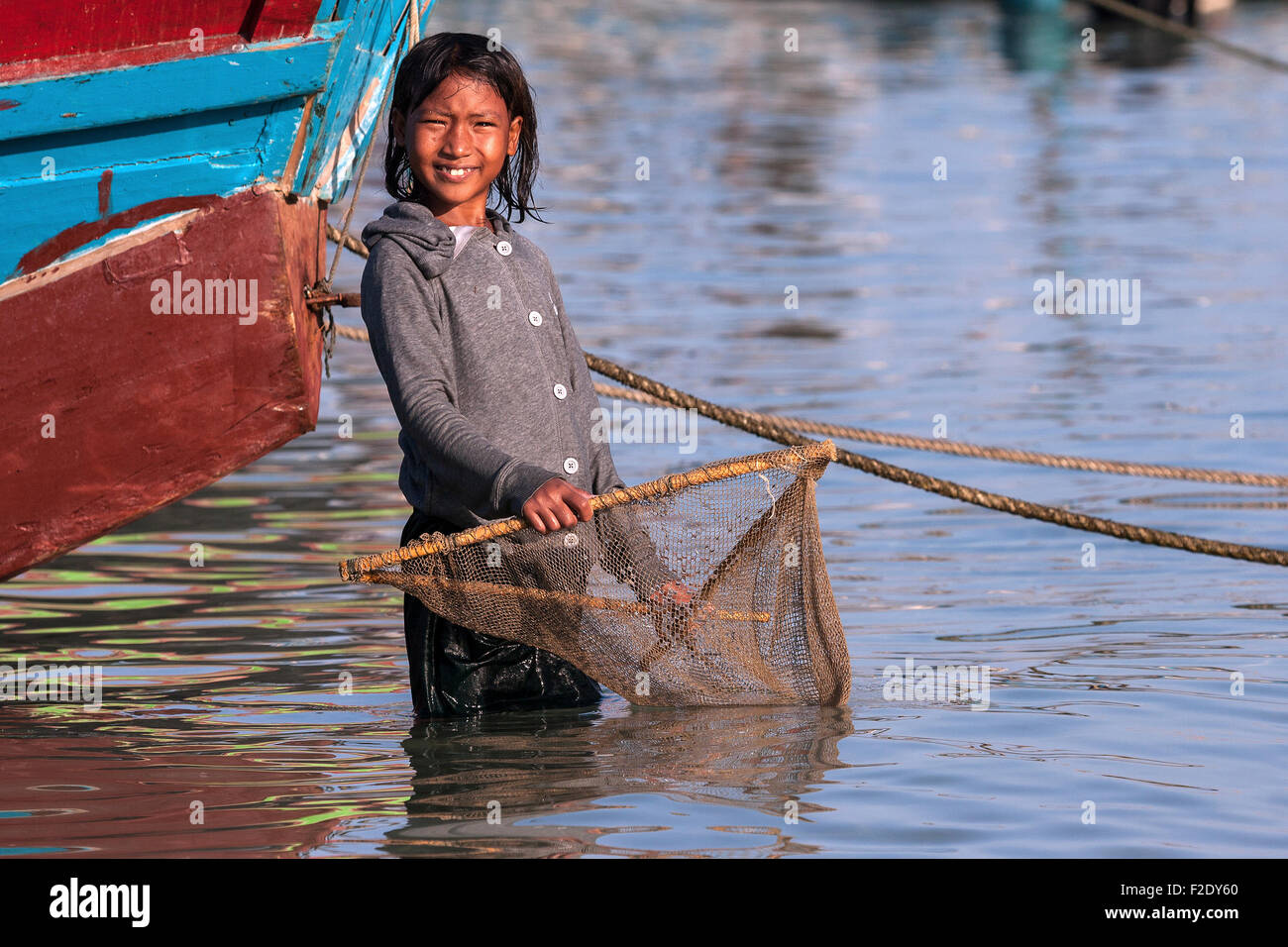 Local girl with a small fishing net in the water at the beach of the