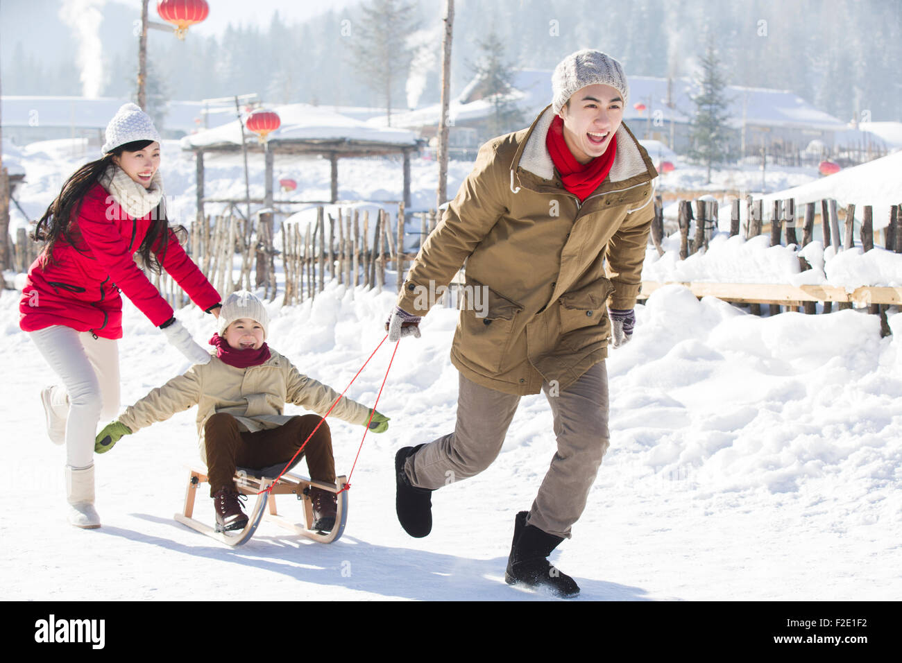 Happy family playing with sled in the snow Stock Photo - Alamy