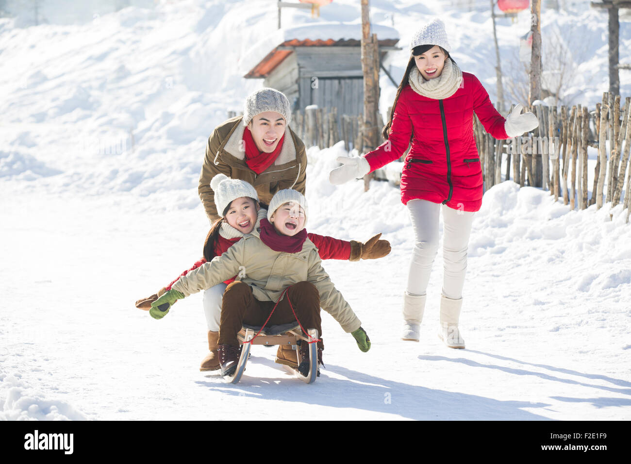 Happy family playing with sled in the snow Stock Photo - Alamy