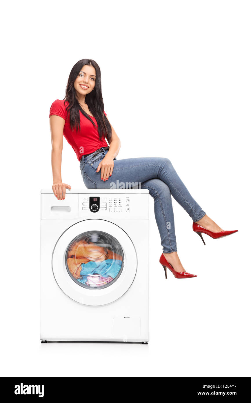 Full length portrait of a beautiful young woman sitting on a washing machine and looking at the camera Stock Photo