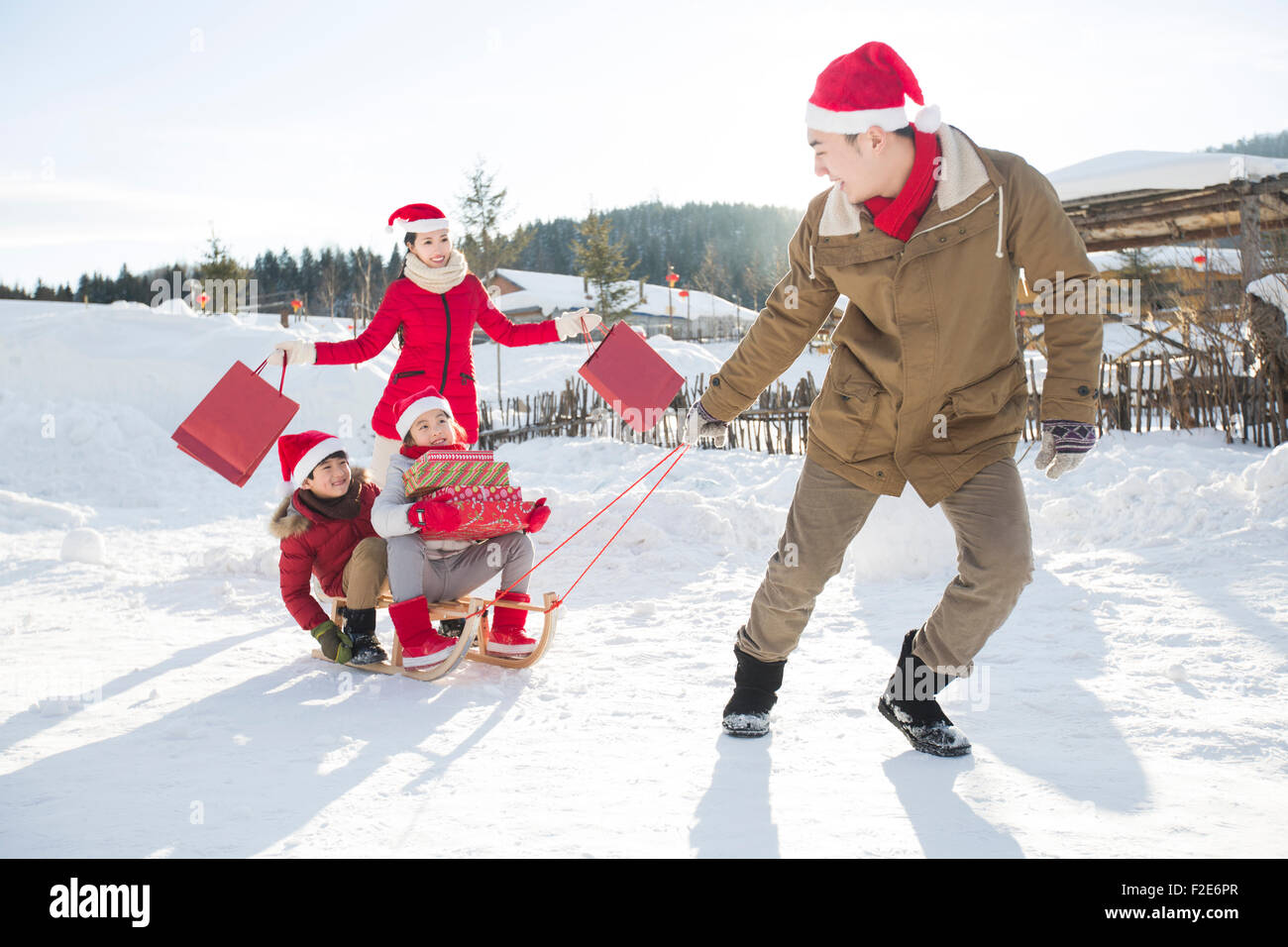 Happy family carrying Christmas Presents with sled Stock Photo