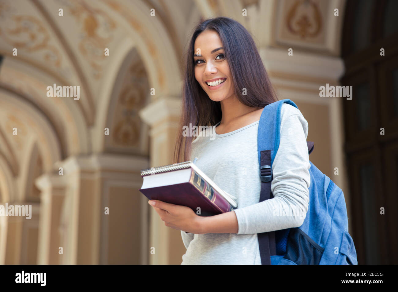 Portrait of a smiling female student standing outdoors and looking at ...