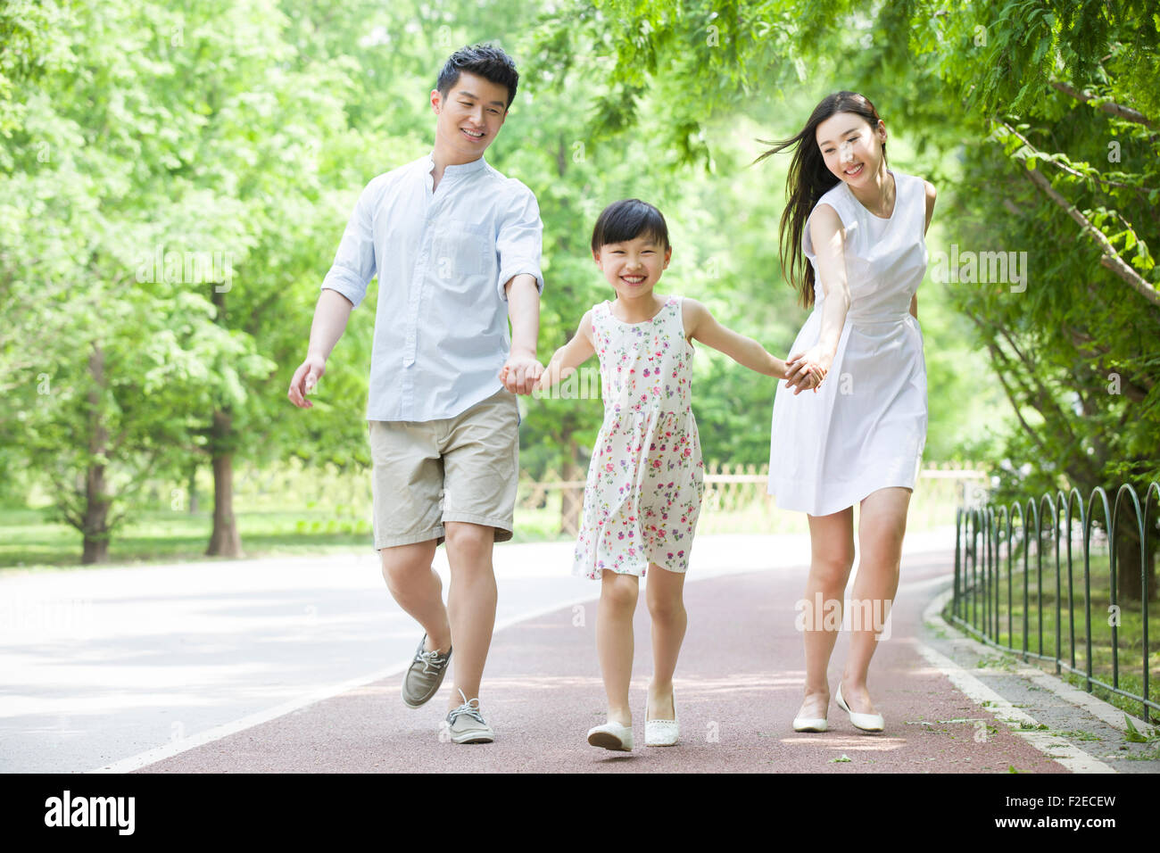 Happy young family walking together in park Stock Photo - Alamy