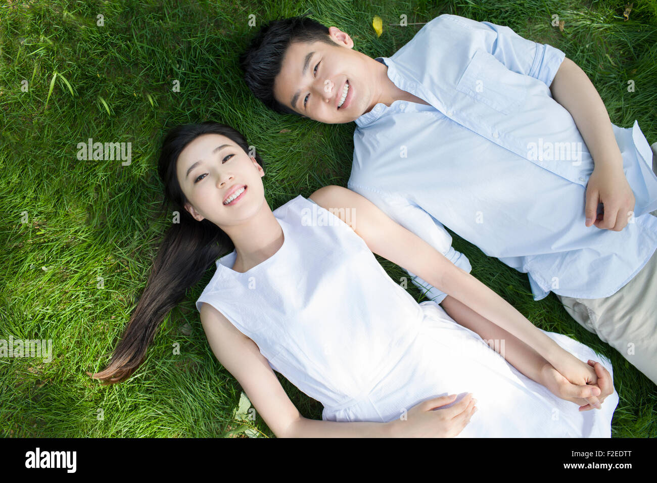 Happy young couple lying on grass Stock Photo - Alamy