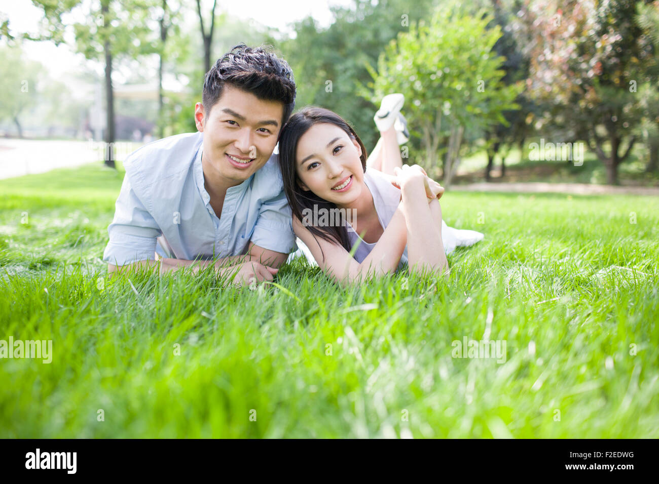 Happy young couple lying on grass Stock Photo - Alamy