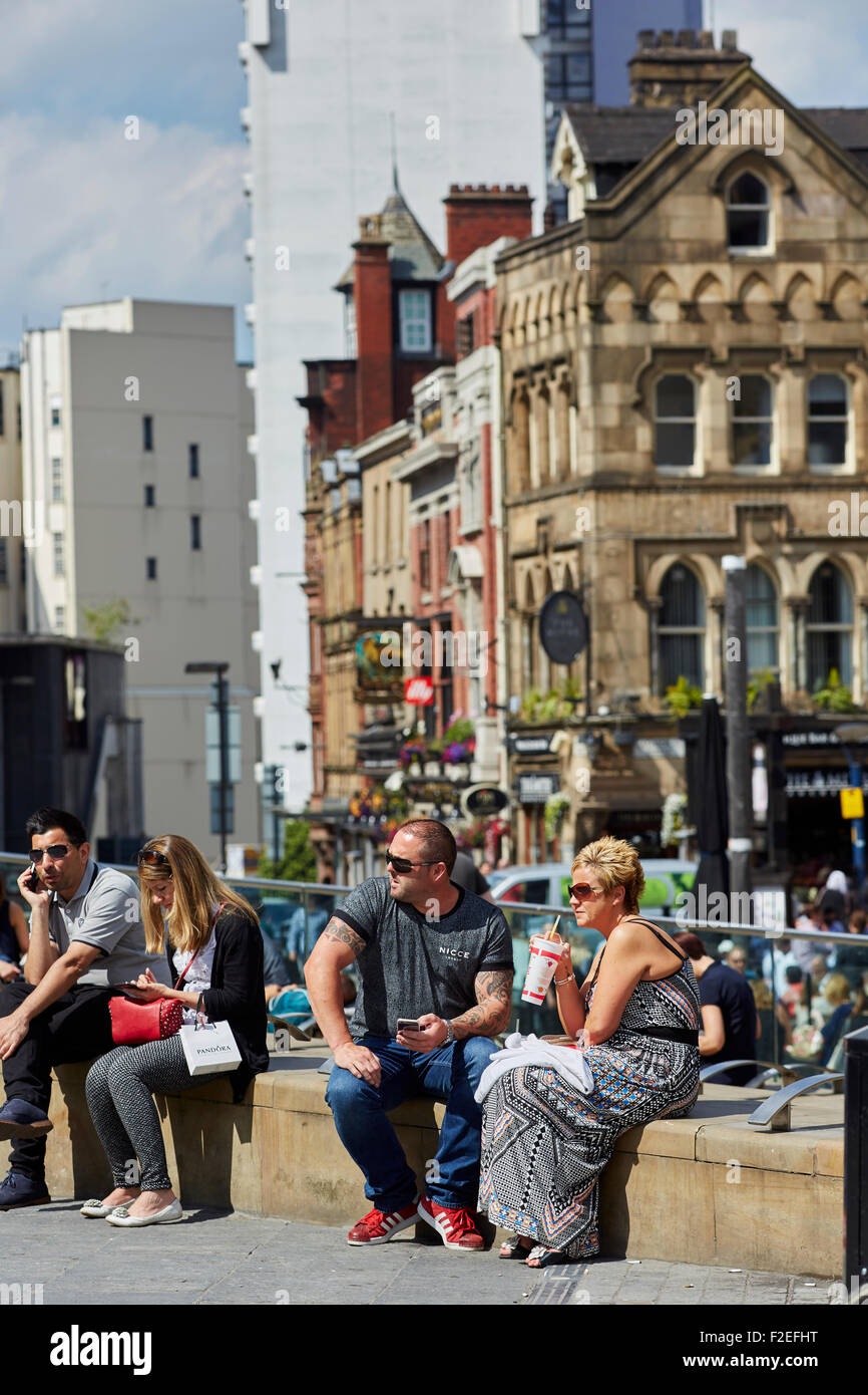People relaxing in the sun at Manchester city centre's Exchange Square   UK Great Britain British United Kingdom Europe European Stock Photo