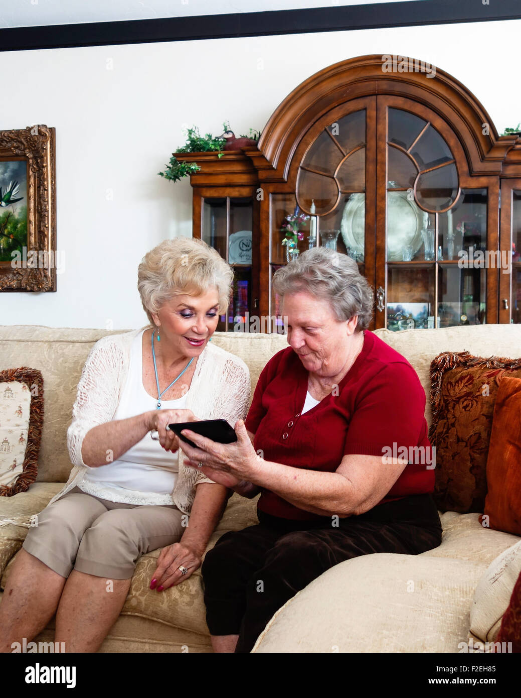 Two Caucasian senior women, sisters, figure out how to use a Kindle Fire. USA Stock Photo