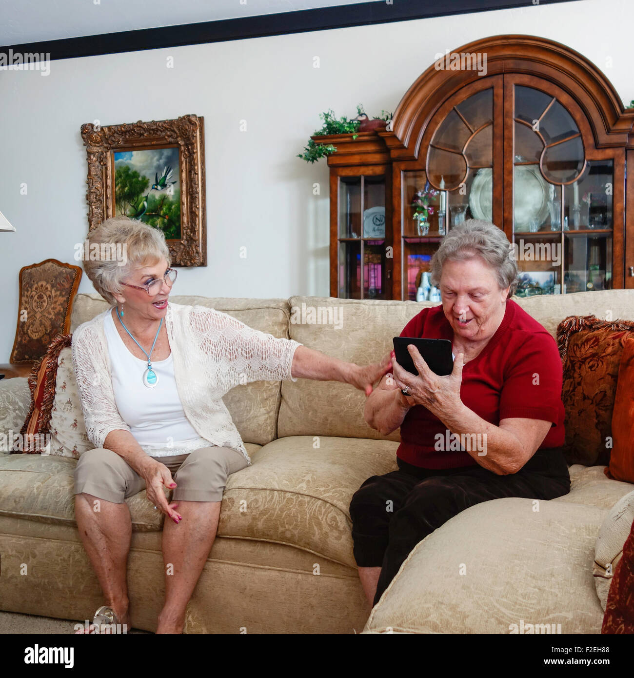 Two Caucasian senior women, sisters, figure out how to use a Kindle Fire. USA. Stock Photo