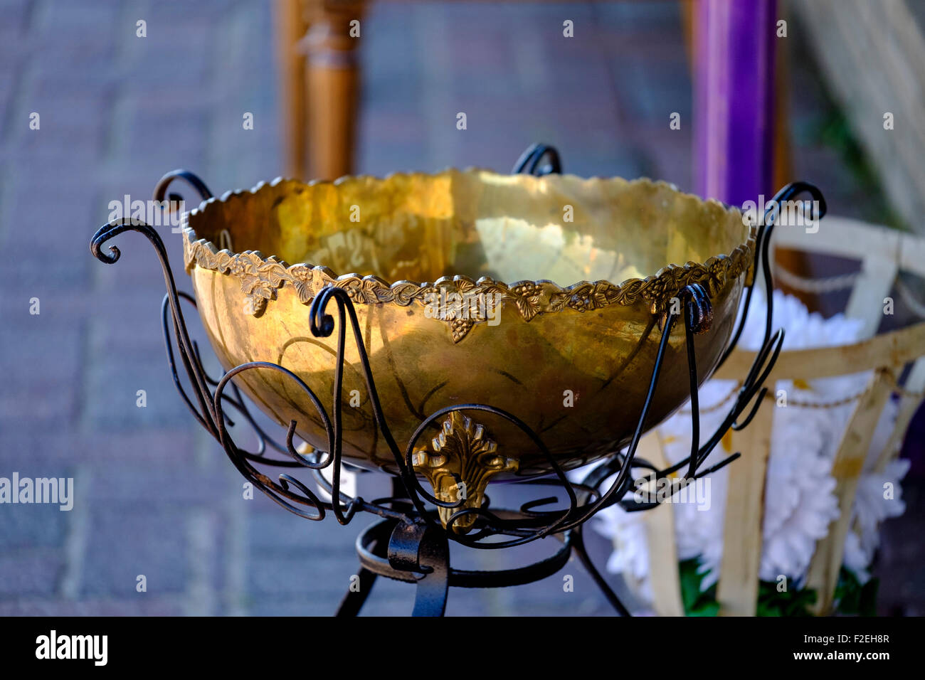 An antique brass bowl in a stand holder sitting on sidewalk in front of antique shop in Bethany, Oklahoma, USA. Stock Photo
