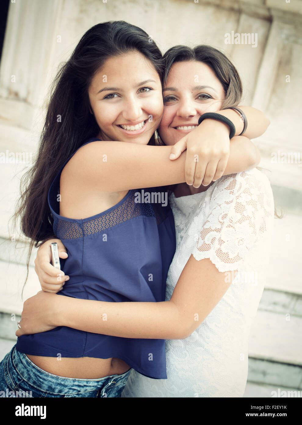 Two sisters embracing and smiling looking into camera Stock Photo