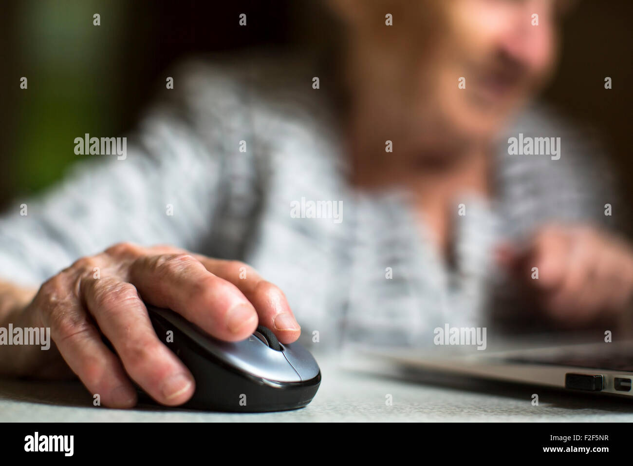 Closeup of the hand of an old woman holding a computer mouse. Stock Photo